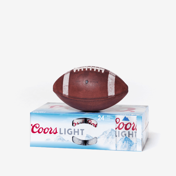 Ballon de football posé sur un pack de bière Coors Light, sur fond blanc.