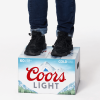 Person wearing jeans and black shoes standing on top of a Coors Light beer case against a white background.
