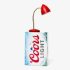 Lampe rouge posée sur un pack de bière Coors Light, sur fond blanc.